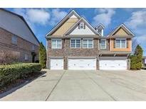Three-story townhome with brick facade and attached three-car garage, manicured landscaping at 805 Pleasant Hill Nw Rd # 343, Lilburn, GA 30047