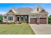 Charming home featuring a well-manicured lawn, stone accents, and a two-car garage with a basketball hoop at 101 River Walk Pkwy, Euharlee, GA 30145