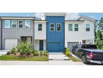 Charming townhome featuring a blue accent section, one-car garage, and well-maintained landscaping at 1615 Gunnin Nw Trce, Atlanta, GA 30318