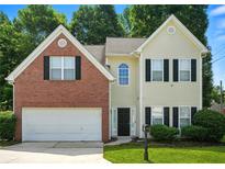 Charming two-story home with brick and siding exterior, an attached garage, and manicured landscaping at 5487 Walnut Lane Ln, Stonecrest, GA 30038