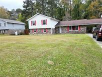 Split-level home with brick and siding, features a front yard and carport at 7437 Grayson Dr, Riverdale, GA 30296