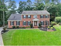 Charming two-story brick home with a manicured lawn, mature trees, and a welcoming front porch at 4211 Schooner Ne Ct, Roswell, GA 30075
