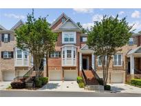 Brick townhome featuring an attached garage, manicured lawn, and well-maintained landscaping at 2969 Rivergreen Se Ln # 23, Atlanta, GA 30339