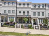 Beautiful brick townhome with manicured landscaping, a covered porch, and black iron fencing at 5836 Sandy Springs Cir, Atlanta, GA 30328