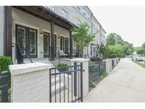 Charming townhouse exterior featuring painted brick, covered front porch, and stylish iron fence at 5836 Sandy Springs Cir, Atlanta, GA 30328