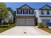 Two-story townhome featuring a stone veneer, double garage and manicured landscaping at 4098 Haleston Rd, Duluth, GA 30097