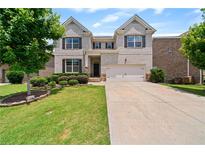 Charming two-story home with light brick exterior, well-manicured lawn, and attached two car garage at 2090 Beckham St, Cumming, GA 30041