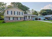 Two-story home featuring a well-manicured lawn, tan siding, brick accents, and a convenient attached carport at 130 Mimosa Dr, Fayetteville, GA 30214