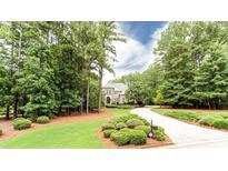 View of exterior with mature trees, landscaped yard and circular driveway leading to a brick home at 35 Inverleigh Row, Covington, GA 30014