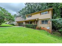 Charming two-story home with a well-manicured lawn and attached garage, nestled among mature trees at 2116 Twin Falls Rd, Decatur, GA 30032