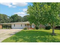 Charming single-story home with a well-maintained lawn, a covered carport, and mature trees at 6160 King Arthur Dr, Douglasville, GA 30135