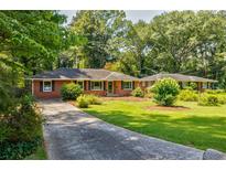 Charming brick home with well-manicured lawn, mature trees, and long driveway at 2343 Hunting Valley Dr, Decatur, GA 30033