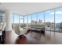 Bright living room featuring a wraparound window, hardwood floors, and a comfortable sectional sofa with beautiful city views at 1080 Peachtree Ne St # 2710, Atlanta, GA 30309
