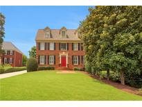 Charming two-story brick home with a well-manicured lawn, red door, and classic design at 4045 Boles Creek Dr, Duluth, GA 30096