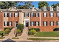 Attractive brick townhome featuring a well-maintained lawn, black shutters, and a welcoming front entrance at 5990 Eagle Tiff Ln, Sugar Hill, GA 30518