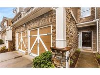 Stunning townhome exterior featuring stone facade, two-car garage and inviting entrance with beautiful landscaping at 6038 Mayfield Se Way, Mableton, GA 30126