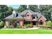 Stately brick home with manicured lawn, lush landscaping and elegant architectural details at 10020 Normandy Ln, Suwanee, GA 30024
