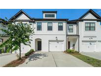 Beautiful townhome with white painted brick, a two-car garage, and manicured landscaping creates great curb appeal at 160 Auburn Gate Ln, Auburn, GA 30011