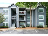 Three-story condo building featuring light gray siding, white trim, balconies, and staircase entryway at 5207 Santa Fe Pkwy, Sandy Springs, GA 30350