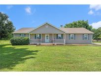 Charming single-story home featuring a well-manicured lawn and inviting front porch with rocking chairs at 487 Laney Rd, Locust Grove, GA 30248