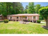 Charming brick home featuring a well-manicured front yard with mature trees and established landscaping at 655 Stone Harbor Sw Pkwy, Marietta, GA 30060