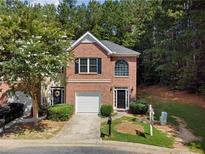 Charming two-story townhome with brick facade, attached garage, and beautifully landscaped front yard at 4221 Rogers Creek Ct, Duluth, GA 30096