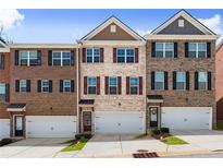 Three-story brick townhomes featuring individual garages and manicured lawns under a bright blue sky at 2227 Foley Park St, Snellville, GA 30078