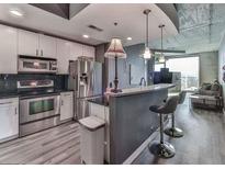 Modern kitchen with stainless steel appliances, light cabinets, bar seating, and industrial style lighting at 361 17Th St # 1121, Atlanta, GA 30363