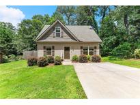 Charming home featuring manicured lawn, inviting front door, and a neatly paved driveway, surrounded by lush greenery at 2850 Winchester Dr, Cumming, GA 30041