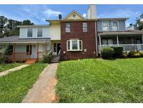 Charming two-story townhome with brick facade and inviting front entrance, surrounded by lush landscaping at 8170 Canyon Forge Dr, Riverdale, GA 30274