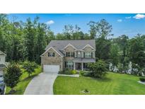 Charming two-story home with a well-manicured lawn, mature trees, and a driveway leading to an attached garage at 297 Aylesbury Blvd, Mcdonough, GA 30252