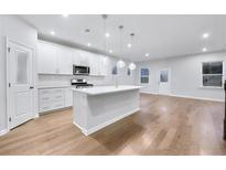 Bright, modern kitchen with white cabinetry, stainless steel appliances, and a large center island with pendant lighting at 6096 Marigold Way, Atlanta, GA 30349