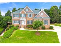 Charming brick home with a manicured lawn, complemented by lush green landscaping and mature trees at 917 Saints Ct, Marietta, GA 30068