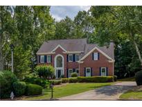 Traditional brick home with manicured landscaping, mature trees and a curved driveway at 755 Creek Wind Ct, Johns Creek, GA 30097