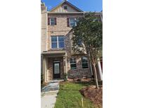 Charming brick townhome featuring a covered entry, multiple windows, and landscaped front yard at 539 Fundao Ln # 28, Lawrenceville, GA 30046
