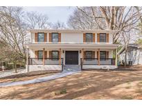 Inviting two-story home featuring a brick facade, a cozy front porch, and a well-manicured front yard at 1885 N Druid Hills Ne Rd, Atlanta, GA 30319