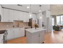 Bright kitchen features stainless appliances, white cabinets, quartz counters, kitchen island, and hardwood floors at 860 Peachtree St # 1103, Atlanta, GA 30308