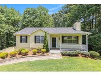 Charming yellow home with well-manicured lawn, front porch, and mature trees at 7420 Bristol Cir, Douglasville, GA 30134
