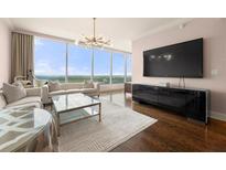 Bright living room features floor-to-ceiling windows with stunning views, modern chandelier, and sleek entertainment center at 3630 Peachtree Ne Rd # 2706, Atlanta, GA 30326