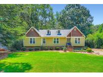 Inviting yellow home with green lawn and mature trees creates a picturesque curb appeal at 350 Lamplighter Se Ln, Marietta, GA 30067