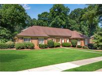 Charming brick home featuring lush green lawn, mature landscaping, and inviting curb appeal at 4063 Penhurst Dr, Marietta, GA 30062