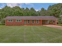 Charming red brick home with covered carport and beautifully manicured lawn at 4601 Lindsey Dr, Powder Springs, GA 30127