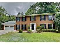 Charming two-story brick home featuring a well-manicured lawn and a two-car garage, complete with traditional black shutters at 650 Lake Forest Ct, Roswell, GA 30076