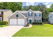 Charming two-story home featuring a manicured lawn, complemented by an attached two-car garage and lush landscaping at 7000 Foxberry Ln, Roswell, GA 30075