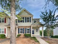 Charming townhome featuring manicured landscaping, neutral siding, dark shutters and a covered front porch at 2438 Suwanee Pointe Dr, Lawrenceville, GA 30043