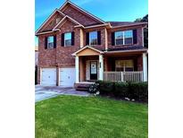 Charming brick two-story home featuring an attached two-car garage, front porch, and well-maintained lawn at 4295 Trillium Wood Trl, Snellville, GA 30039