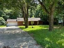 View of the home's exterior with an attached garage and mature trees on a grassy lot at 2842 Jordan Forest Trail Northwest, Lawrenceville, GA 30044