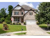 Charming two-story brick home featuring a well-manicured lawn, two-car garage, and inviting front porch with rocking chairs at 521 Andes Ln, Canton, GA 30114