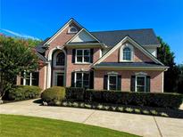 Elegant brick home with manicured landscaping, dark shutters, and a driveway leading to the front entrance at 801 Windsor Rdg, Canton, GA 30115