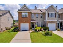 Charming two-story townhome featuring a brick facade, manicured lawn, and attached garage at 176 Oak Green Dr, Lawrenceville, GA 30044